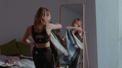 a woman standing in front of a mirror holding a towel