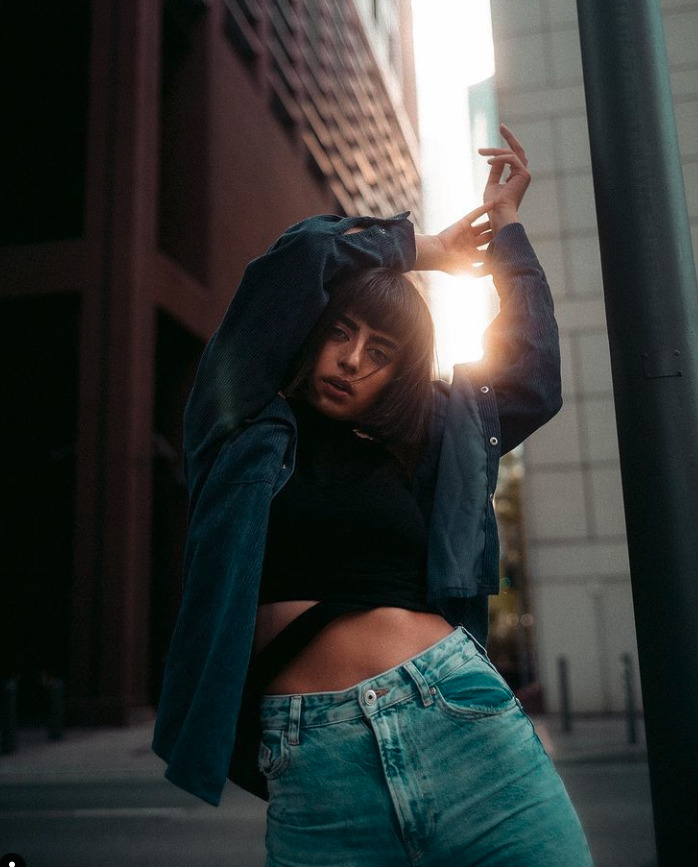 a woman in jeans posing in front of a street light