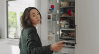 a woman standing in front of an open refrigerator