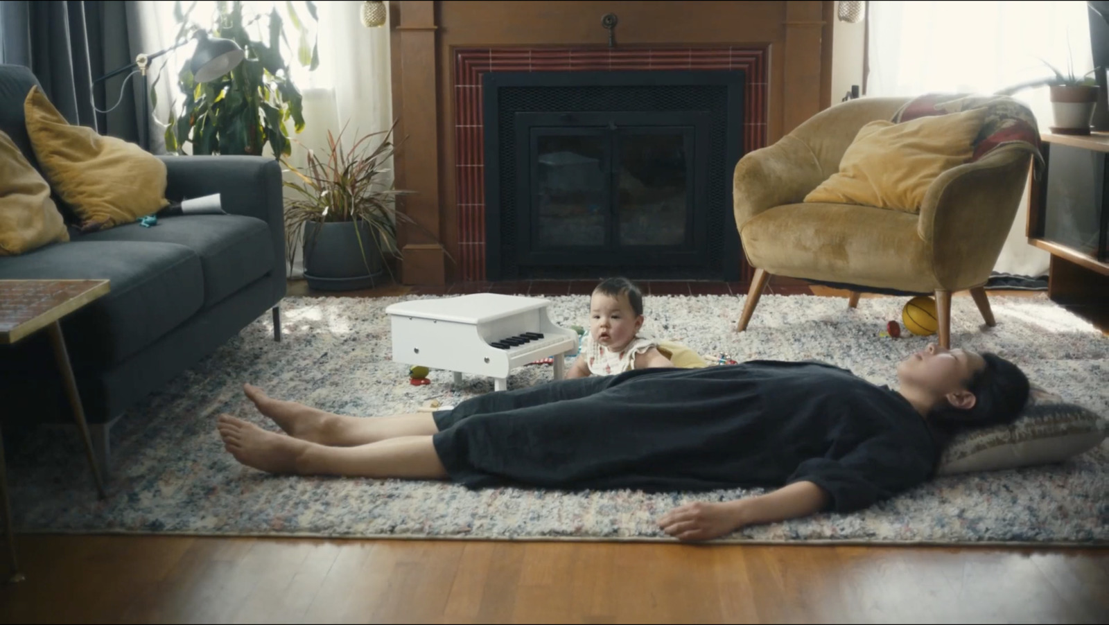 a woman and a baby laying on a rug in a living room