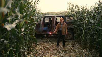 a man standing next to a truck in a corn field