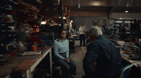 a man sitting on a chair in a room filled with tools