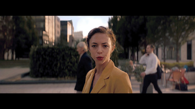 a woman in a yellow jacket walking down a street