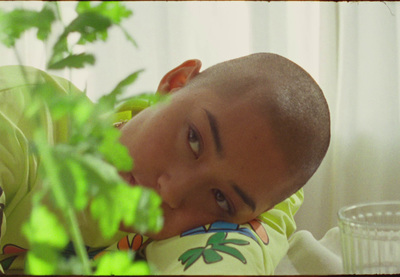 a young man laying on top of a bed next to a plant