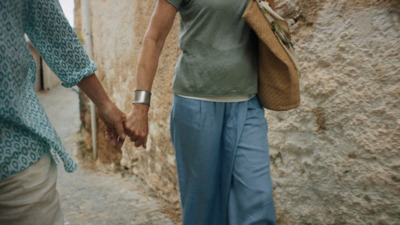 a couple of people walking down a street holding hands