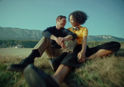 a man and woman sitting on a bench in a field