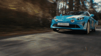 a blue sports car driving down a road