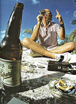 a man sitting on the ground with a bottle of beer