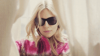 a woman in a pink sweater and black sunglasses