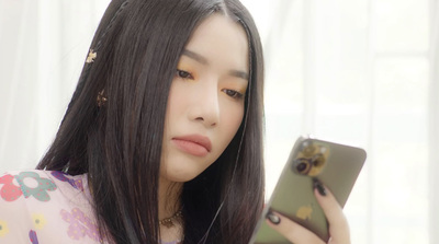 a woman with long black hair looking at her phone