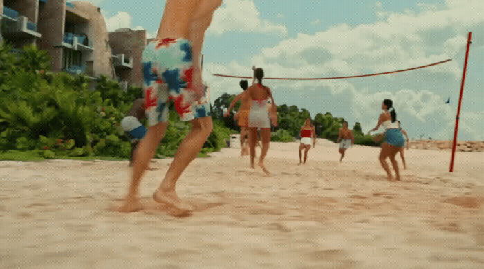 a group of people playing volleyball on the beach