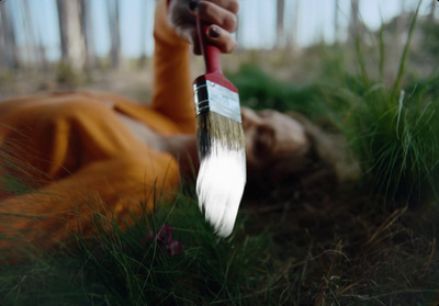 a person laying on the ground holding a paint brush