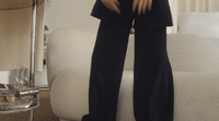 a woman in a black suit standing on a white couch