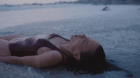 a woman laying on the beach in the water