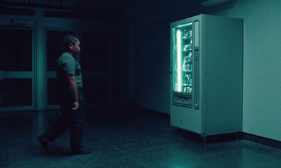 a man standing next to a vending machine in a dark room