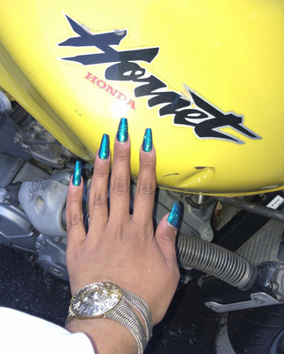 a woman's hand with blue nail polish on a yellow motorcycle