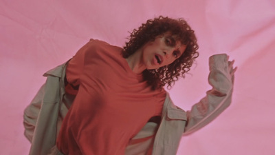 a woman with curly hair wearing a pink shirt