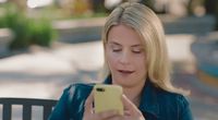 a woman sitting at a table using a cell phone