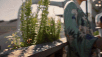 a woman standing on a balcony next to a plant