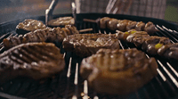 a grill with steaks and skewers cooking on it