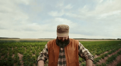 a man with a beard and a hat standing in a field