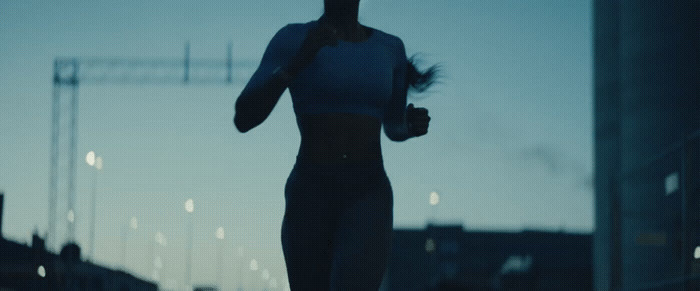 a silhouette of a woman running on a city street