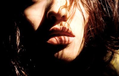 a close up of a woman's face with her hair blowing in the wind