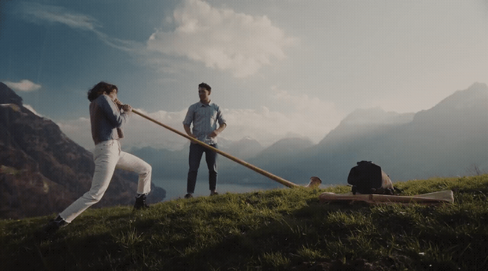 a couple of people standing on top of a lush green hillside