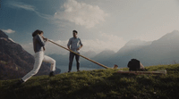 a couple of people standing on top of a lush green hillside