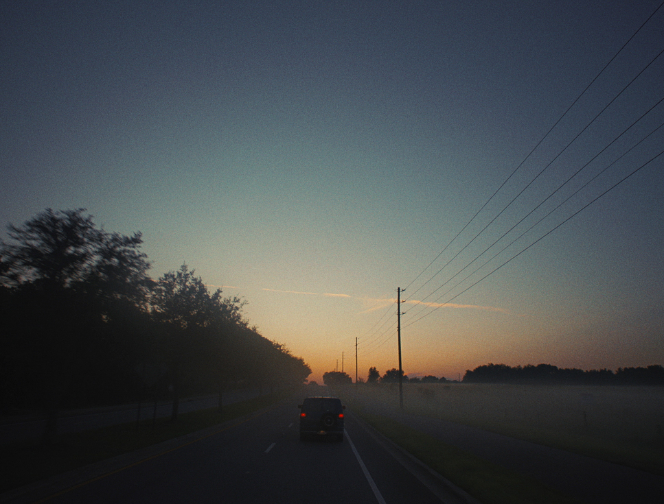 a car driving down a road at sunset