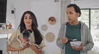 a man and a woman standing in a kitchen with a dog