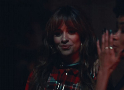 a woman in a red and black plaid shirt clapping