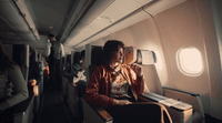 a woman sitting on an airplane seat next to a window