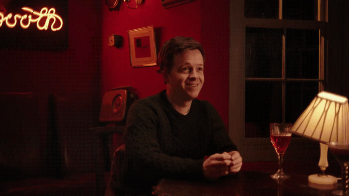 a man sitting at a table with a glass of wine