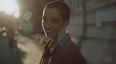 a woman in a brown jacket is smiling at the camera