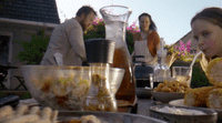 a group of people standing around a table filled with food