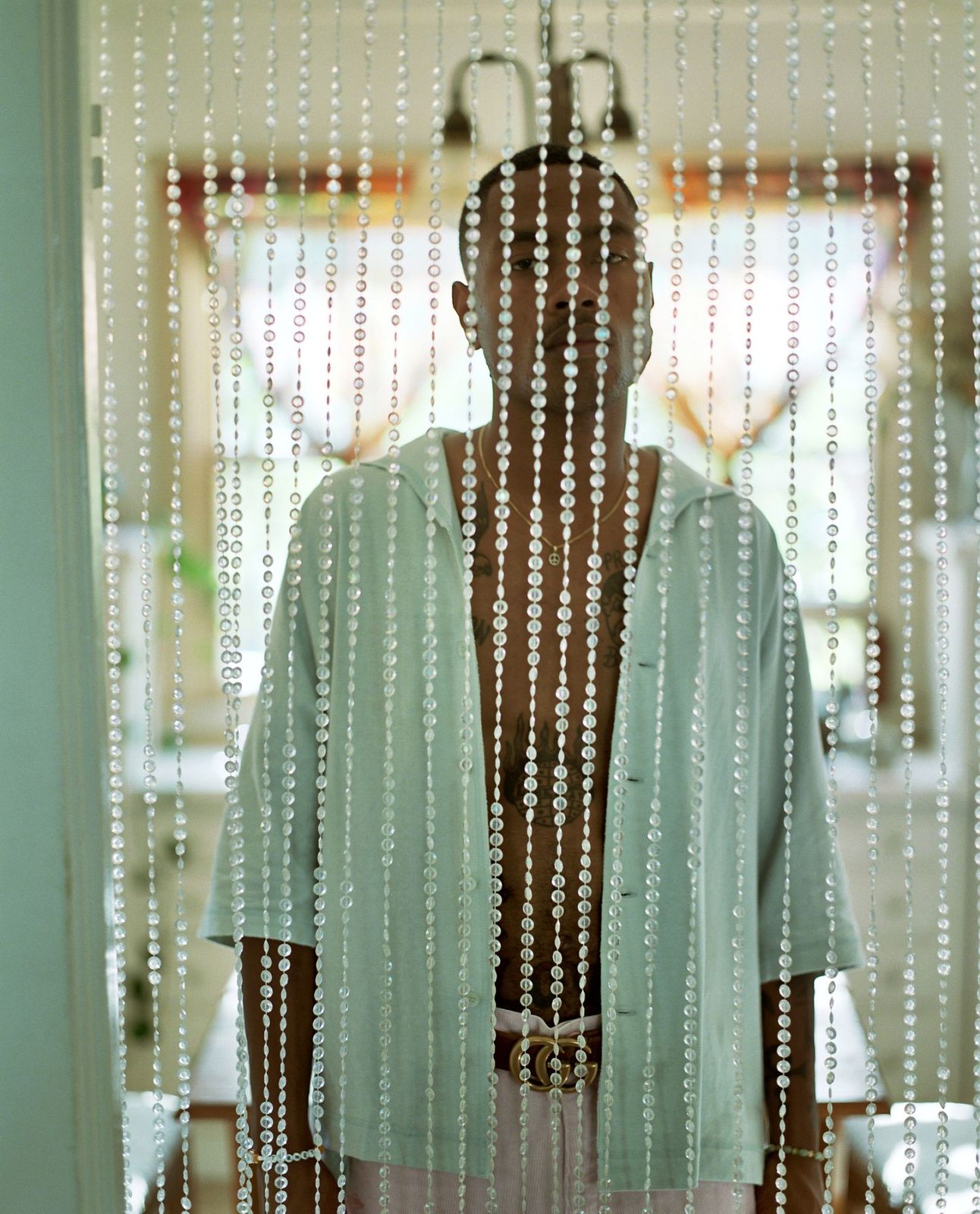 a man standing in front of a window covered in beads