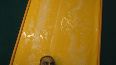 a man standing in front of a yellow surfboard