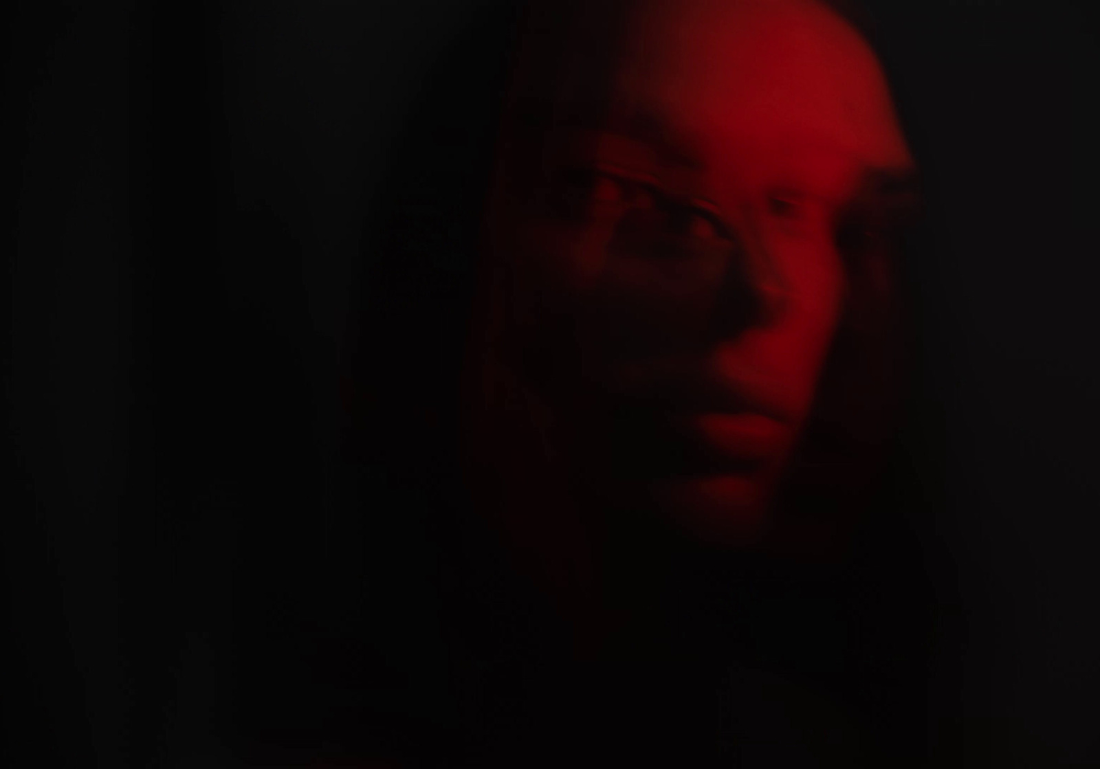 a man in a dark room with a red light on his face