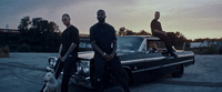 a group of men standing next to a parked car