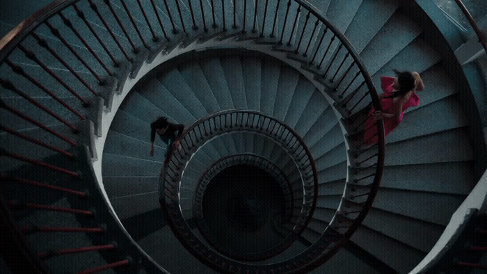 a woman is standing on a spiral staircase