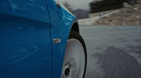 a close up of a blue car driving down a road