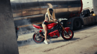 a woman riding a red motorcycle down a street