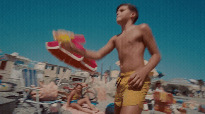 a man standing on a beach holding a red and yellow frisbee