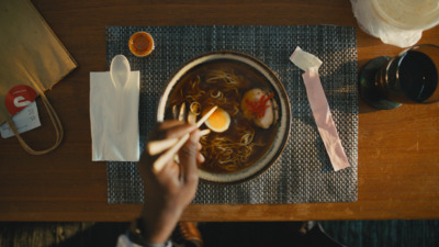 a person is eating noodles with eggs in a bowl