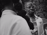 a black and white photo of a man talking to another man