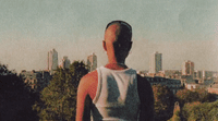 a person standing on a hill with a city in the background