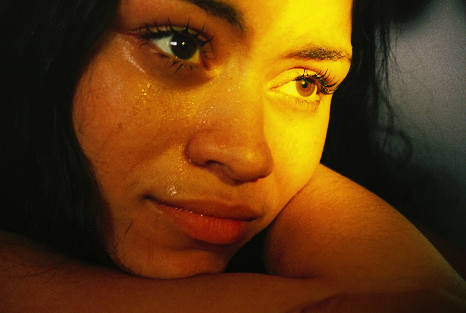 a close up of a woman's face with her hand on her shoulder