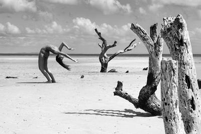 a black and white photo of a person doing a handstand on a beach