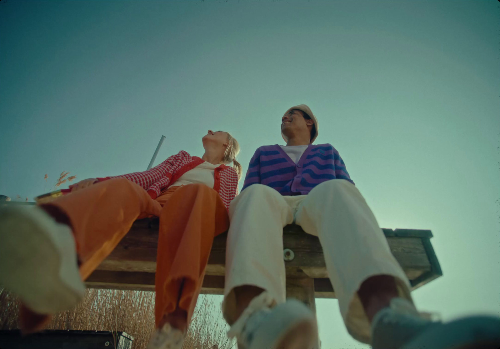 a couple of people sitting on top of a wooden bench